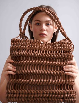 Model holding up brown handbag