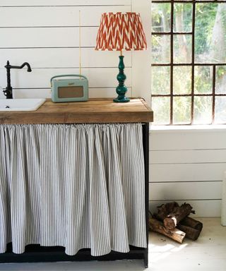 kitchen with striped cabinet curtain and white panelled walls