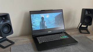 Origin EON17-X v2 gaming laptop resting on a desk between two speakers