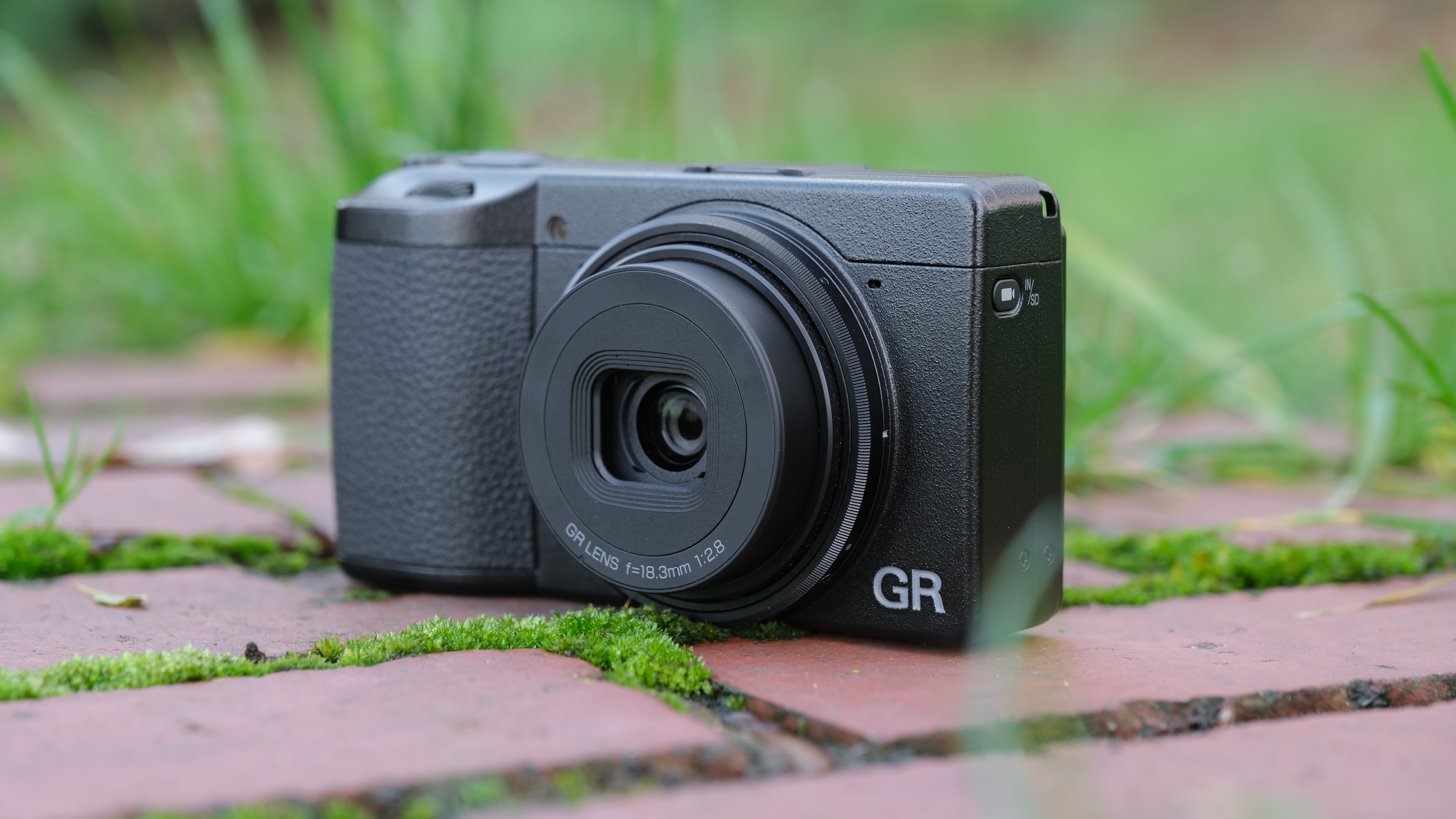 Ricoh GR IV compact camera on a brick wall