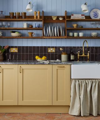 yellow kitchen cabinets with light blue paneling and open wooden shelves and loads of vintage decor