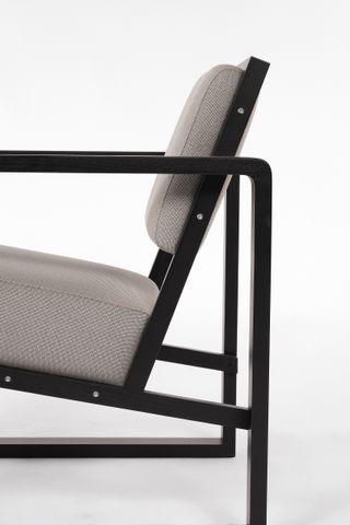 Chair with angular black wooden frame and grey upholstery, shown from the side