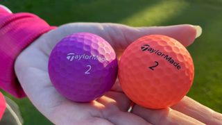 The purple and orange TaylorMade Kalea Golf Ball held on the golf course