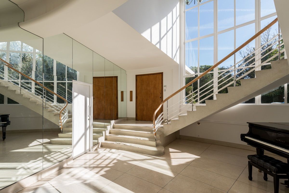 The hallway shows large windows alongside the staircase and mirrored walls