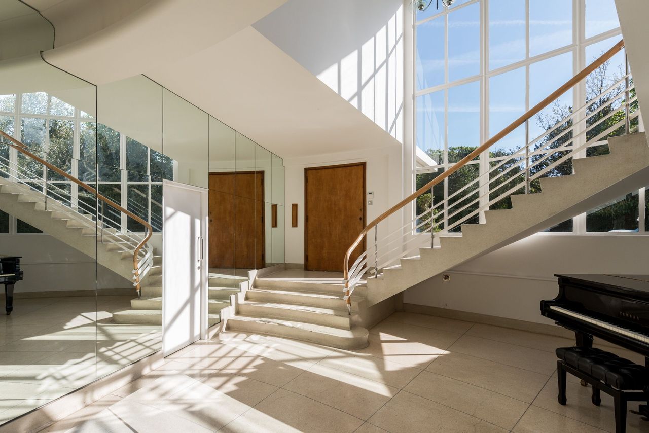 The hallway shows large windows alongside the staircase and mirrored walls