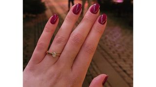 A close up of Digital Beauty Writer, Naomi Jamieson's red almond nails and engagement ring