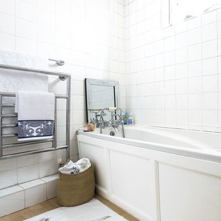 whte bathroom with bathtub and steel towel rack