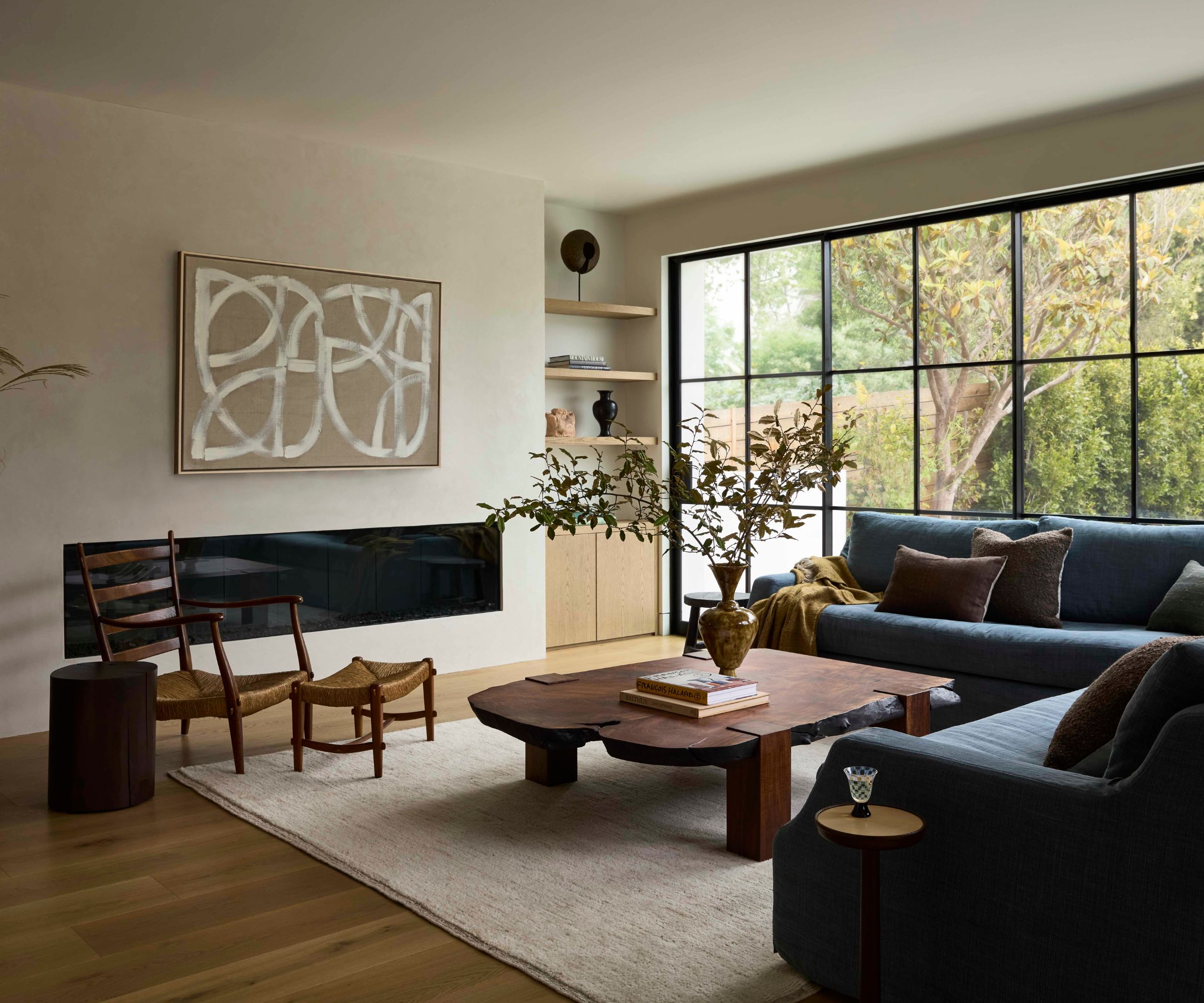 a neutral 'cali wabi sabi' family room with large crittal patio doors and a navy sofa