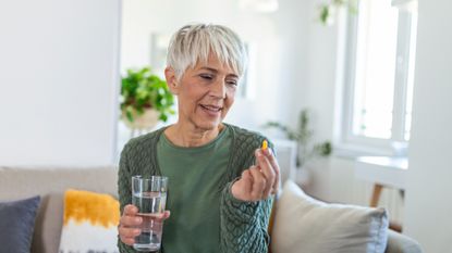 Woman taking a menopause supplement with water