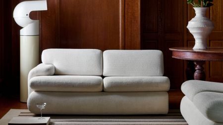 Contemporary white living room furniture and striped rug styled inside of a wood-paneled room