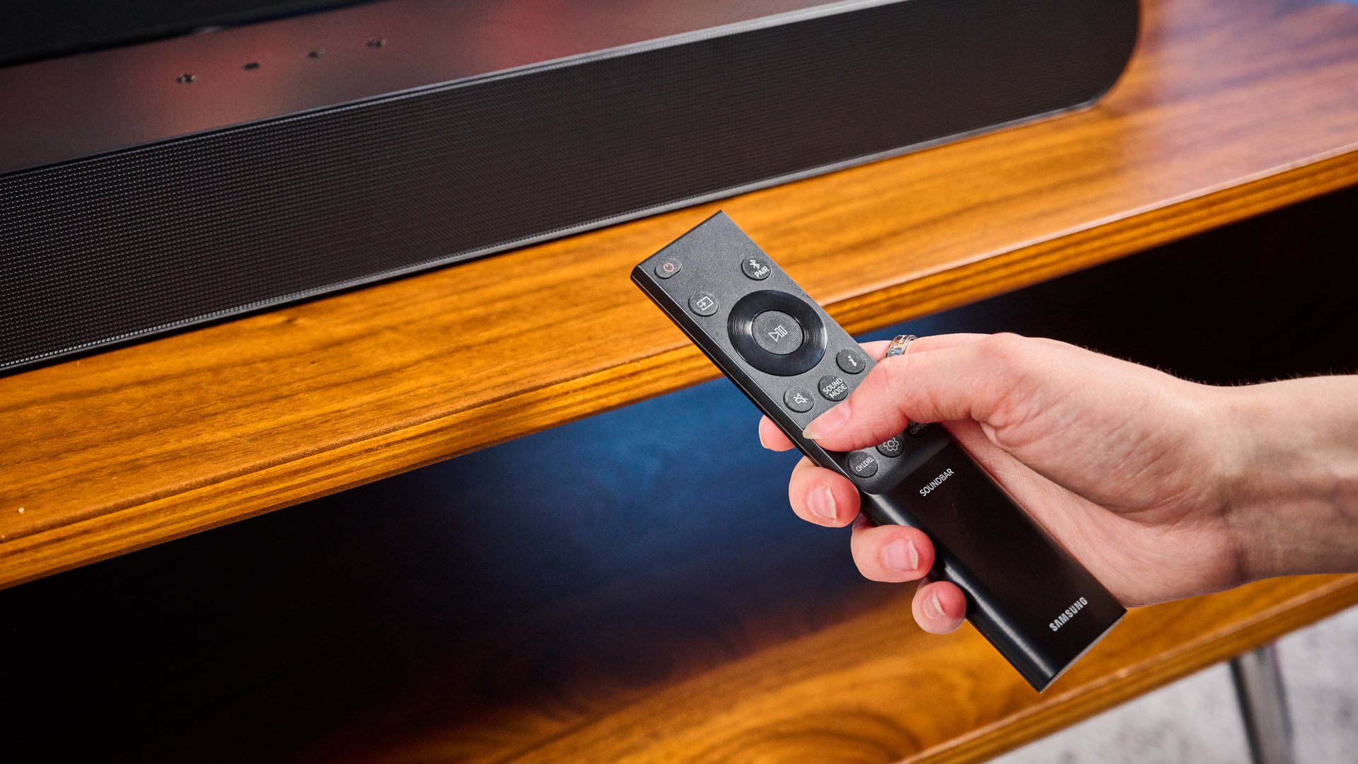 the samsung hw-s60D soundbar photographed on a wooden coffee table with a panasonic tv and a samsung soundbar against a blue background