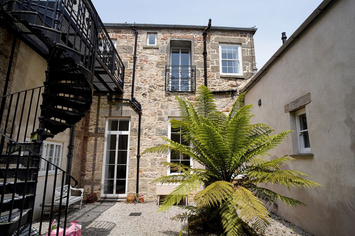 A courtyard with large plants and a metal staircase