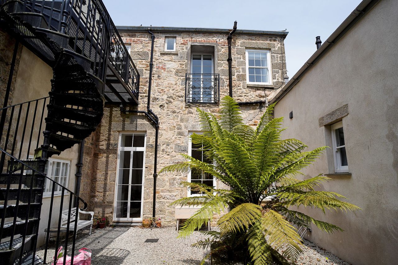 A courtyard with large plants and a metal staircase