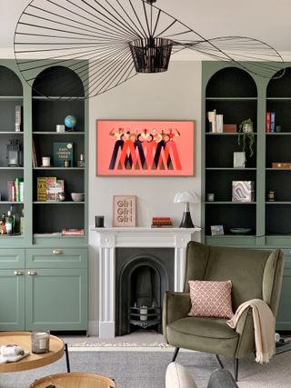 a living room with green arched alcove shelving decorated with books and art work