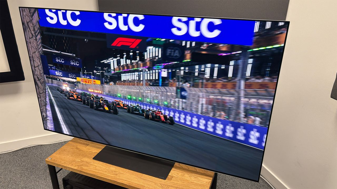 The 65-inch LG G5 OLED TV pictured on a wooden rack. On the screen is a still from Netflix F1 series Drive to Survive.
