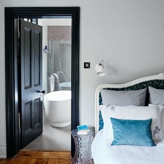 light grey bedroom with open door leading to en-suite bathroom