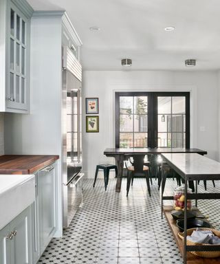A white kitchen with blue cabinets, a black kitchen island, and black dining table and windows
