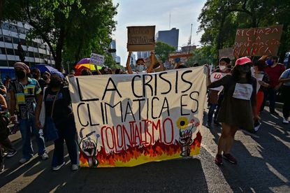 Demonstrators hold sign reading ‘the climate crisis is colonialism’ at Fridays for Future protest in Mexico City