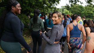 Woman turning to face the camera, laughing with a friend at run club in the rain