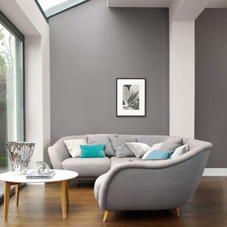 grey living room with a single picture frame décor and a grey sofa with pillows and a white top with wooden legs circle coffee table