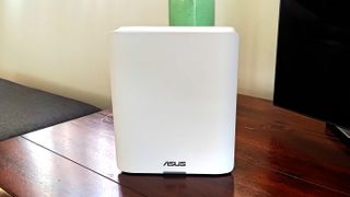 Asus ZenWiFi BT10 from the front on a wooden table wide image