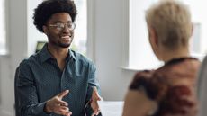 A young man smiles while he's interviewing a financial adviser.