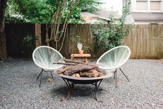 rustic fire pit with two chairs in a backyard