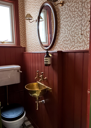 small bathroom with a copper sink and a red wooden wall