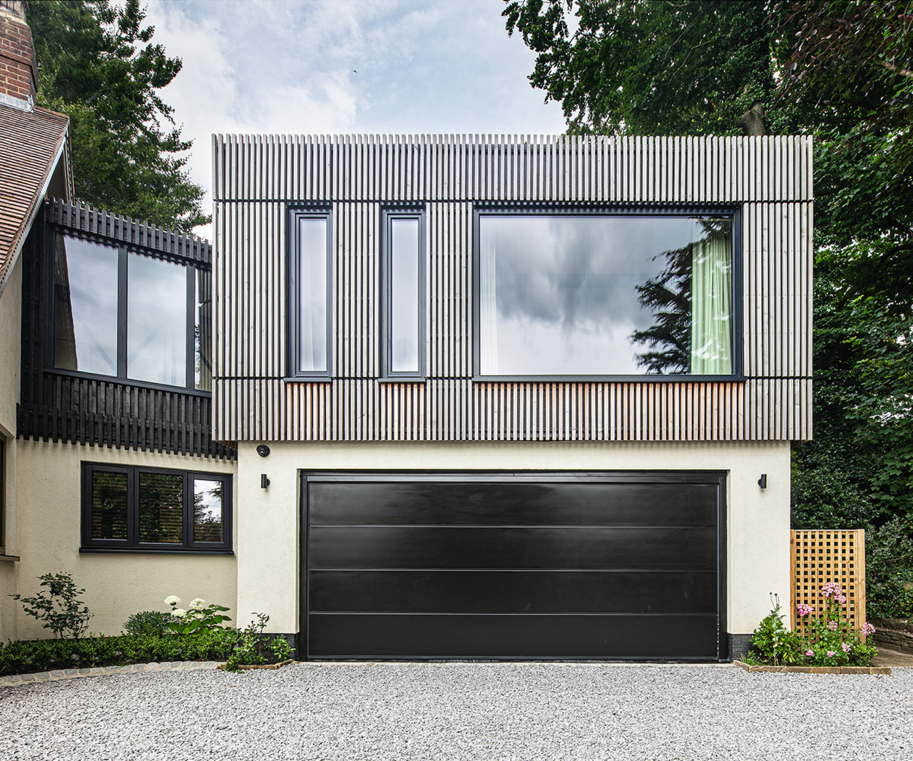 Close-up of one side of the extension, a cladded section with large windows above a black garage door