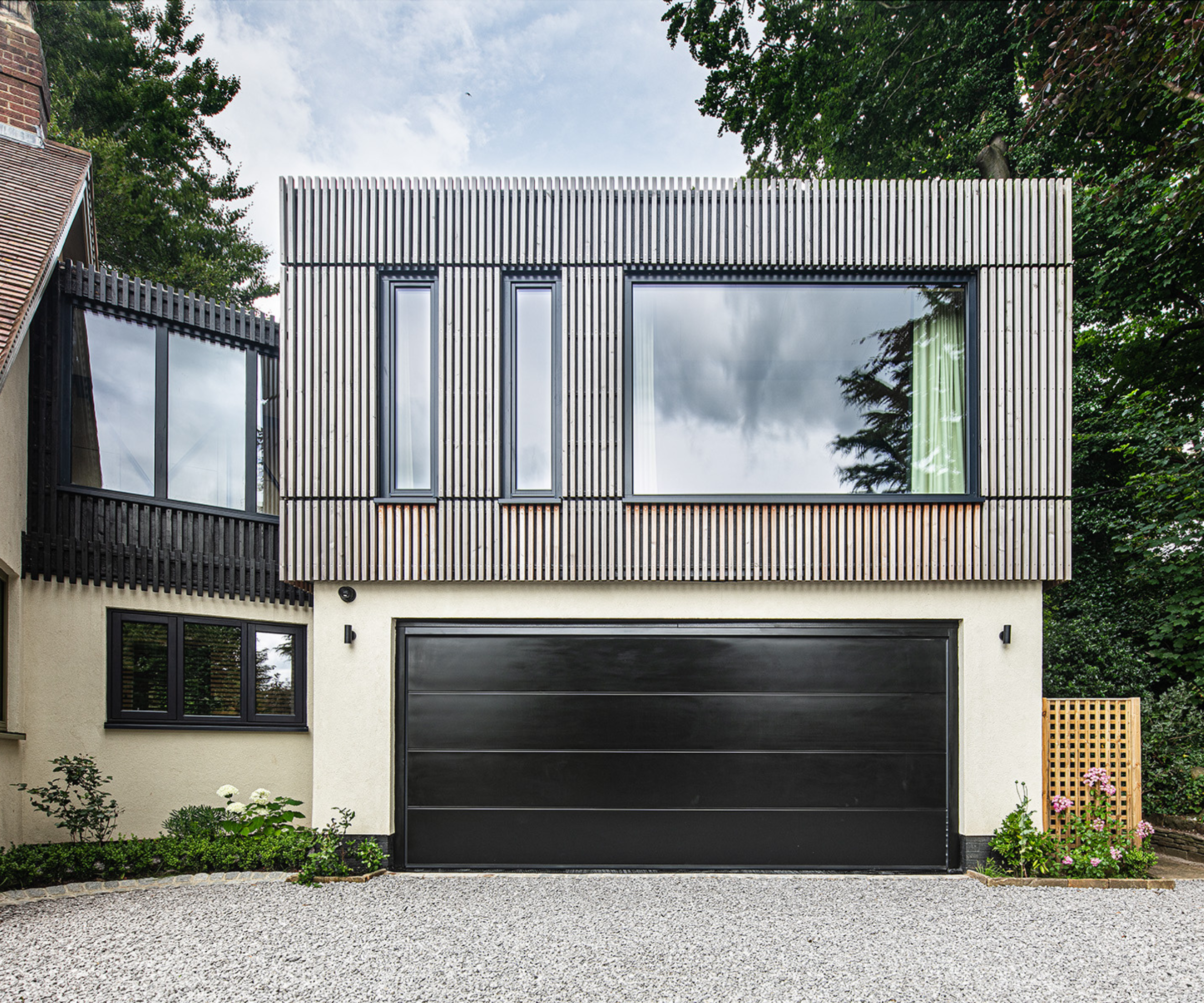 Close-up of one side of the extension, a cladded section with large windows above a black garage door