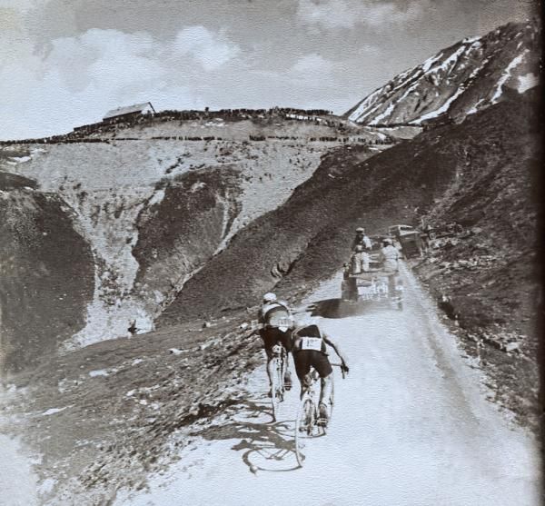 The queen stage of the 1930 Tour de France - stage 16 - was acknowledged as one of the hardest. Andr&eacute; Leducq gained the leaders jersey following the 231km stage which was won by Italian star Alfredo Binda in a time of 9h21'31". In this photograph the leading riders Benoit Faure and Andr&eacute; Leducq can be seen approaching the summit of the Col du Galibier, lined in the distance by thousands of fans eagerly waiting their heros.