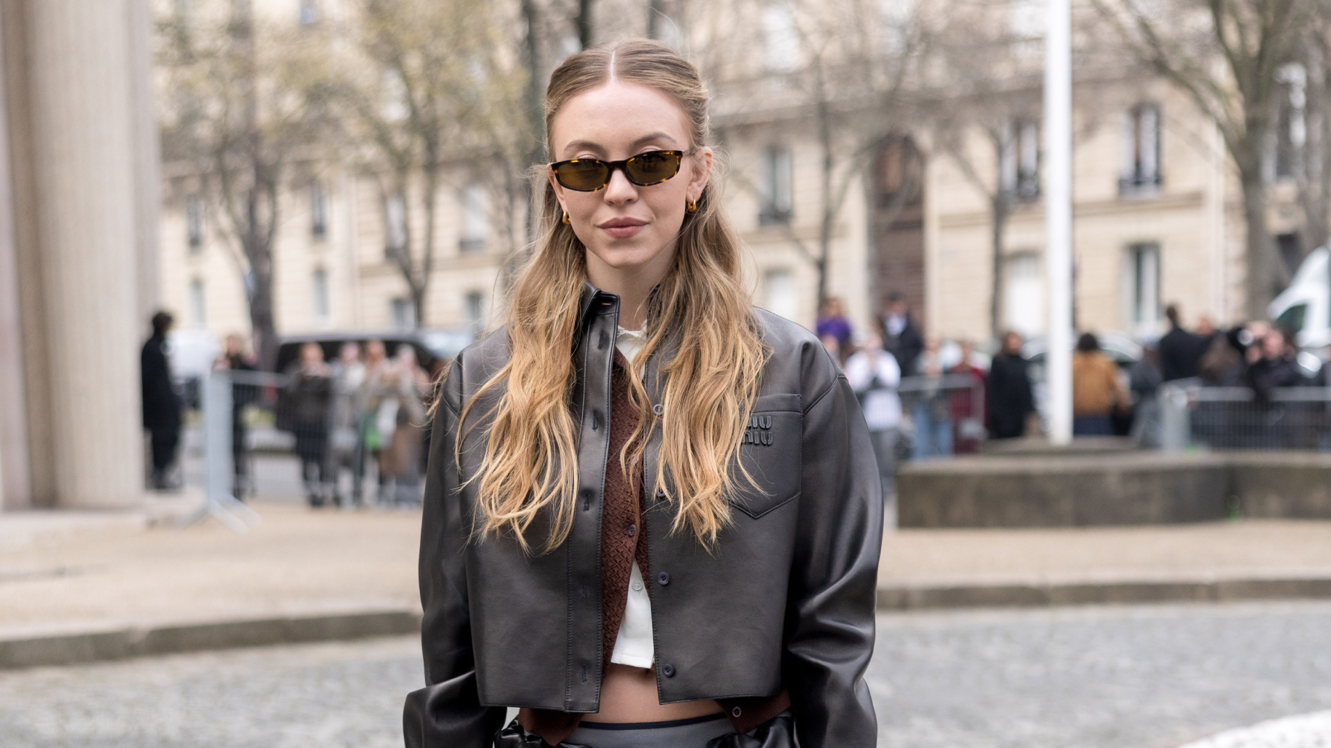 Sydney Sweeney wearing a half-up half down hairstyle and sunglasses.