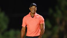 Tiger Woods smiles broadly while wearing an orange Nike shirt