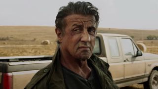 Sylvester Stallone gives intense side eye in front of his truck in Rambo: Last Blood.