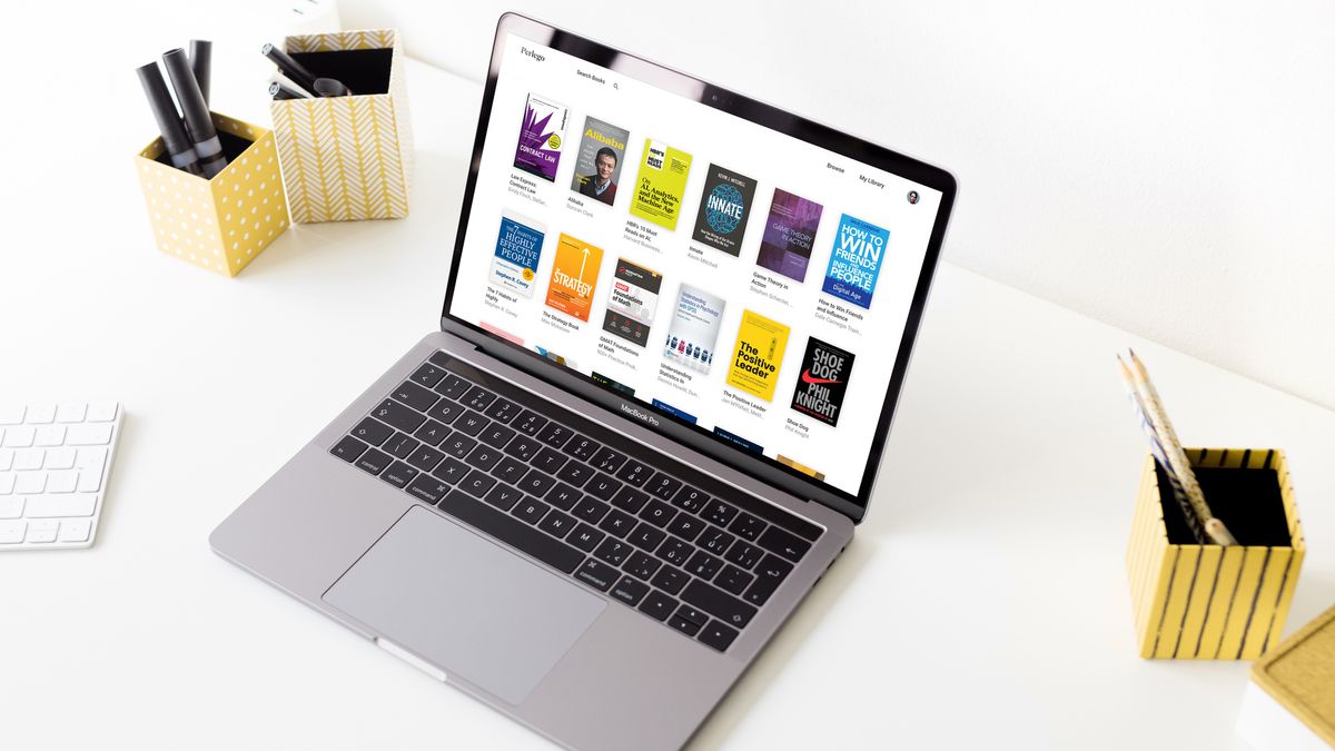 A laptop on a white desk with the Perlego homepage displayed