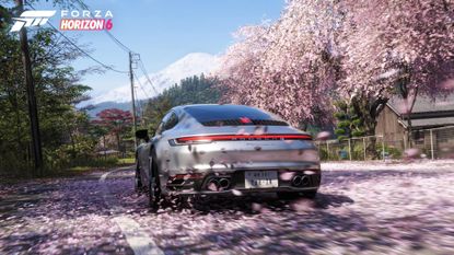 Forza Horizon 6 gameplay shows a silver Porsche driving through cherry blossom petals, and mount Fuji can be seen on the horizon
