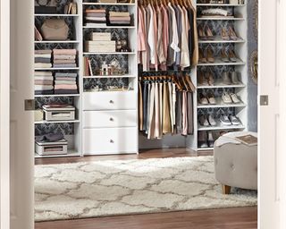 A walk in wardrobe/closet with cream colored textured rug in center of room