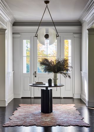 an entryway with a table and statement light