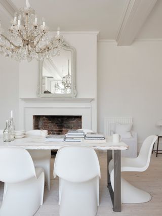 All white dining room with large mirror over the mantle