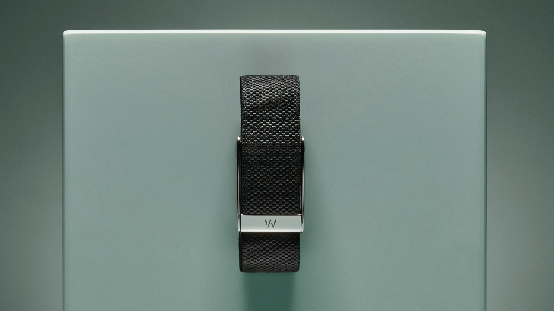 The black fabric Whoop band with silver clasp pinned to a turquoise box