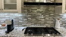 Stovetop in a kitchen with gray tiles