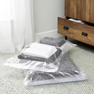 vacuum storage bags filled with clothes on a bedroom floor