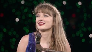 Taylor Swift smiling and looking to her left during the secret song section of the Eras Tour.