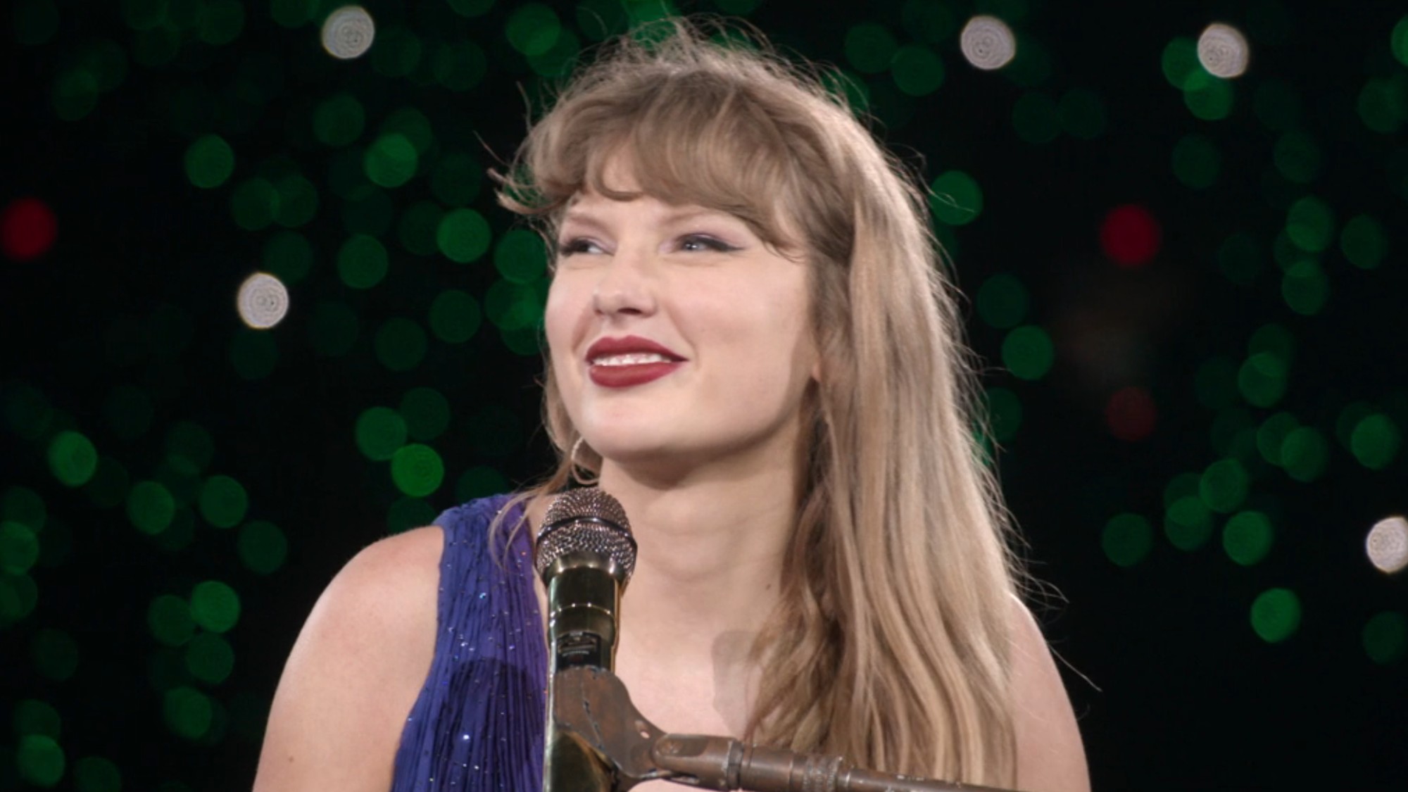 Taylor Swift smiling and looking to her left during the secret song section of the Eras Tour. 