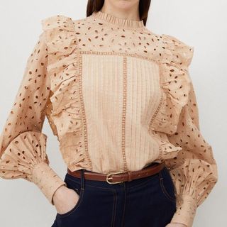 Cropped image of a woman wearing a beige frilly shirt