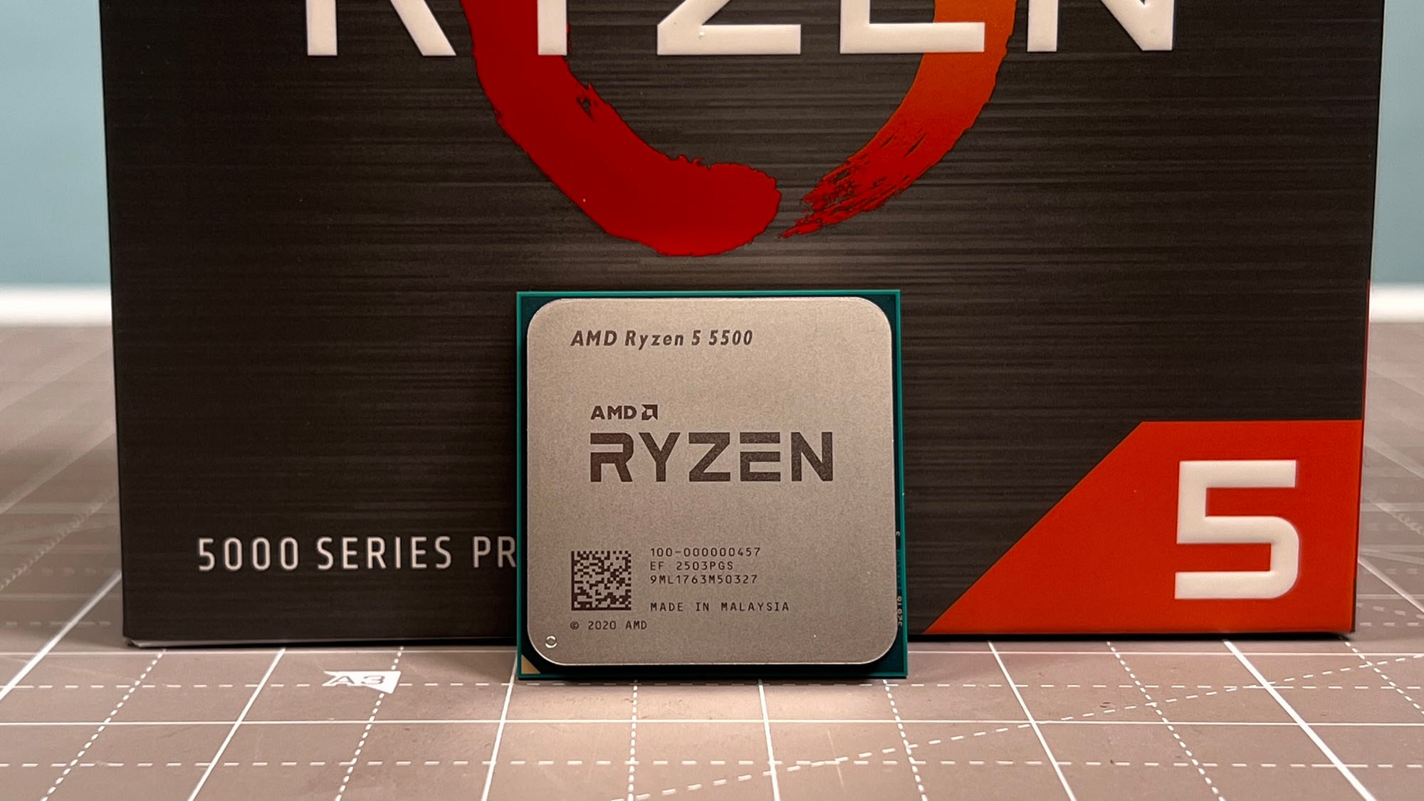 An AMD Ryzen 5 5500 standing upright in front of its retail packaging.