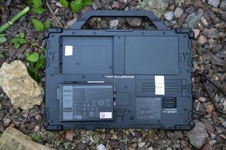 A black Dell Latitude 7330 Rugged Extreme laptop sitting on a rocky surface