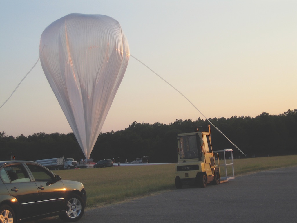 Large white balloon being inflated in a field.