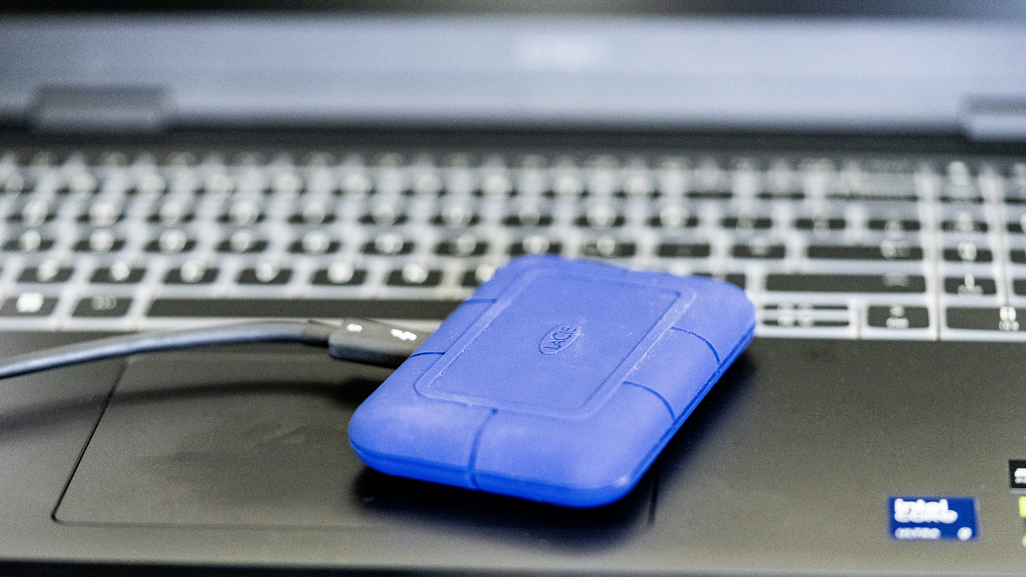 The LaCie Rugged Pro 5 in blue on a laptop and on a white background.