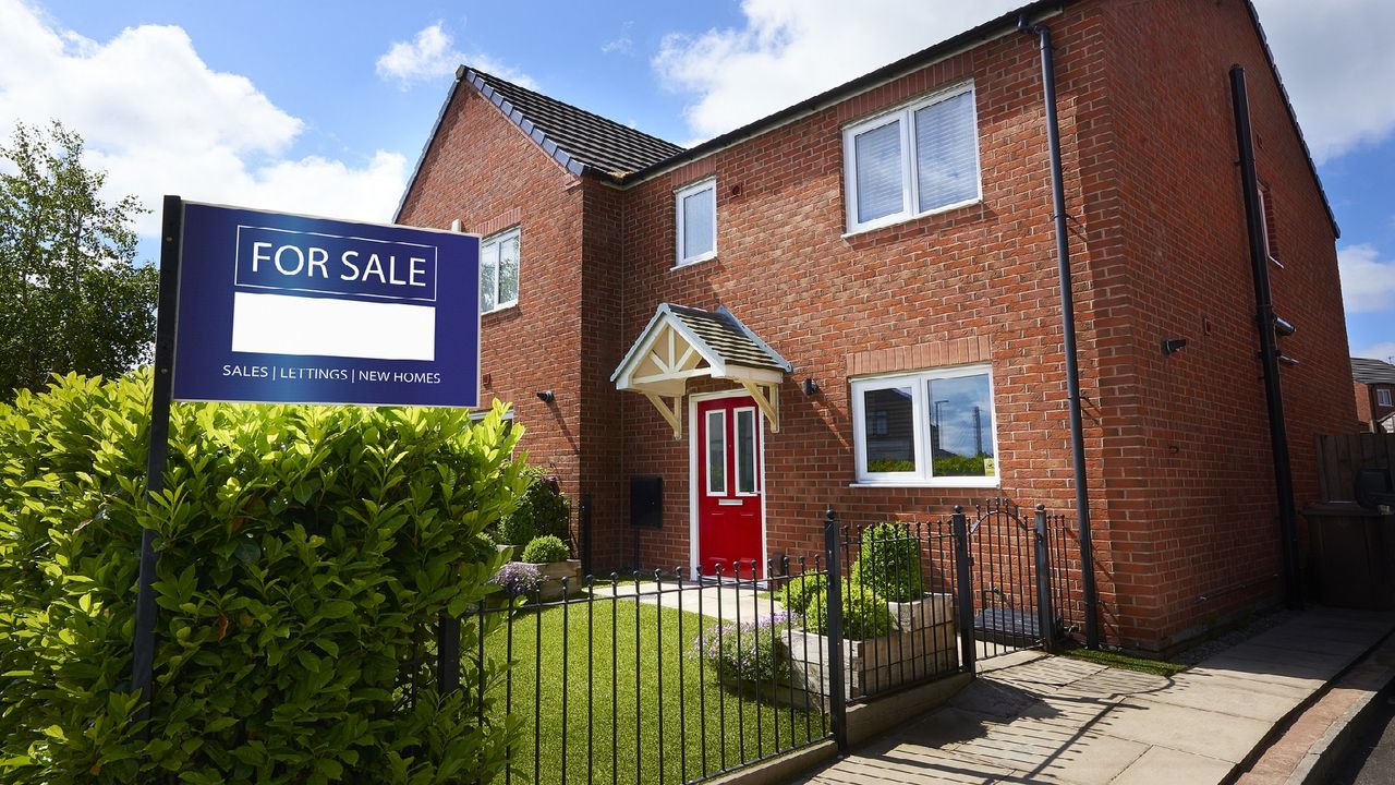 A for sale sign in front of a red brick house.